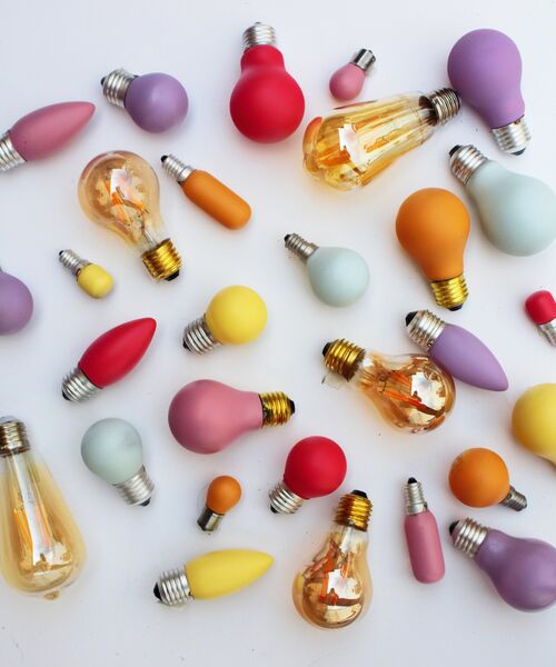 Bunte Glühbirnen in verschiedenen Formen und Farben auf weißem Hintergrund.