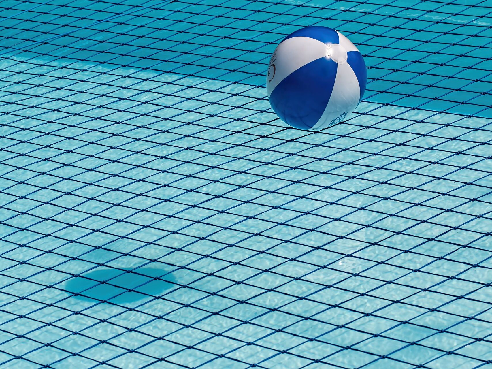 Blau-weißer Wasserball schwimmt in einem Pool mit Kachelmuster.