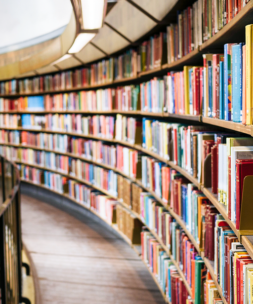 Große Bibliothek mit geschwungenem Regal voller bunter Bücher.