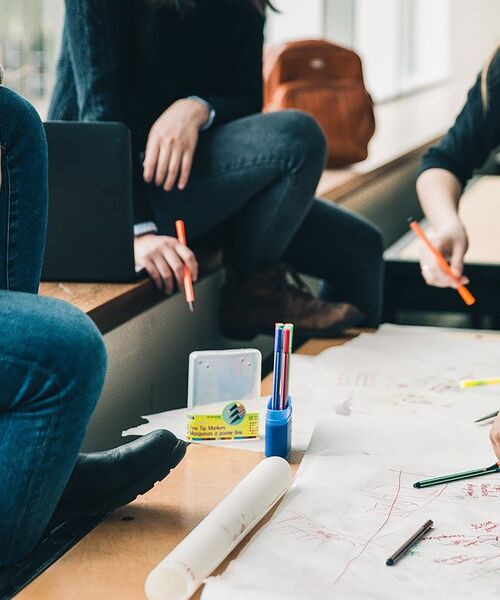 Gruppe von Studierenden arbeitet gemeinsam mit Stiften und Papier an einem Projekt.