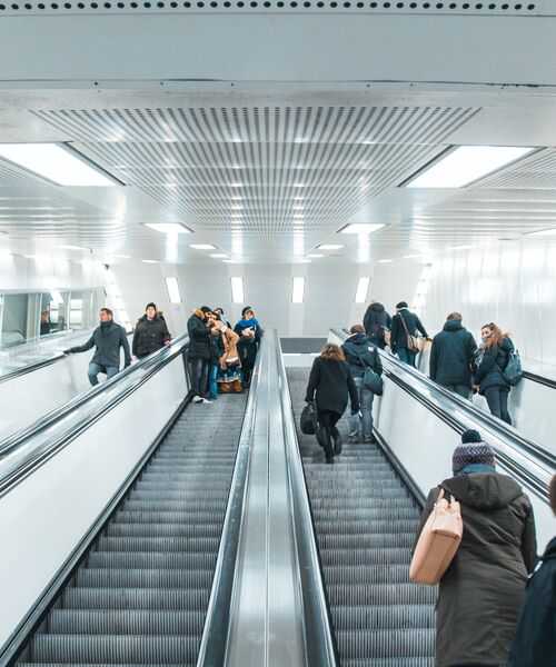 Menschen fahren auf Rolltreppen in einer modernen U-Bahn- oder Bahnhofshalle.