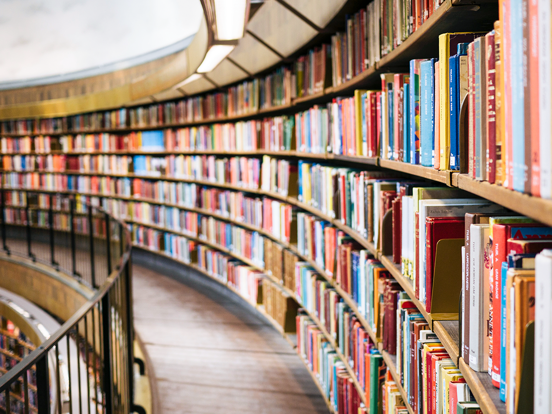 Große Bibliothek mit geschwungenem Regal voller bunter Bücher.