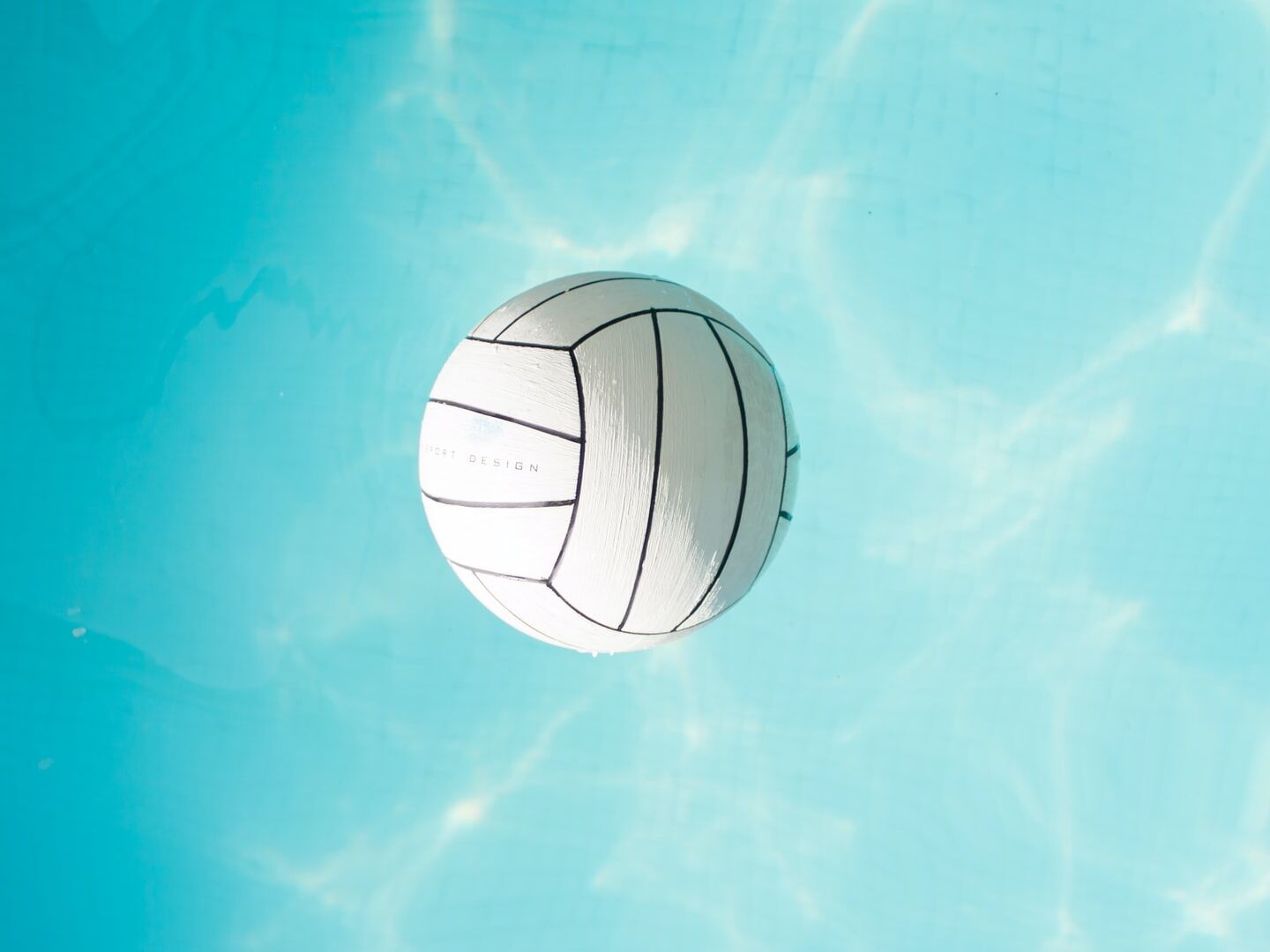 Weißer Volleyball schwimmt im klaren Wasser.
