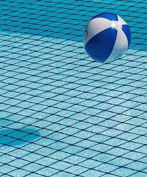 Blau-weißer Wasserball schwimmt in einem Pool mit Kachelmuster.