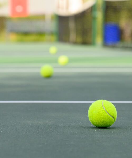 Mehrere gelbe Tennisbälle auf einem Tennisplatz.