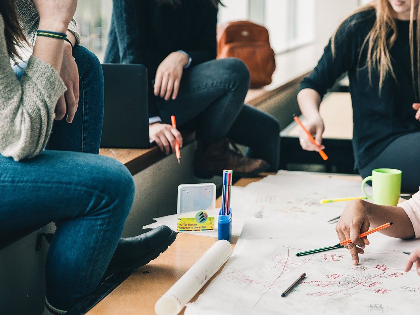 Gruppe von Studierenden arbeitet gemeinsam mit Stiften und Papier an einem Projekt.