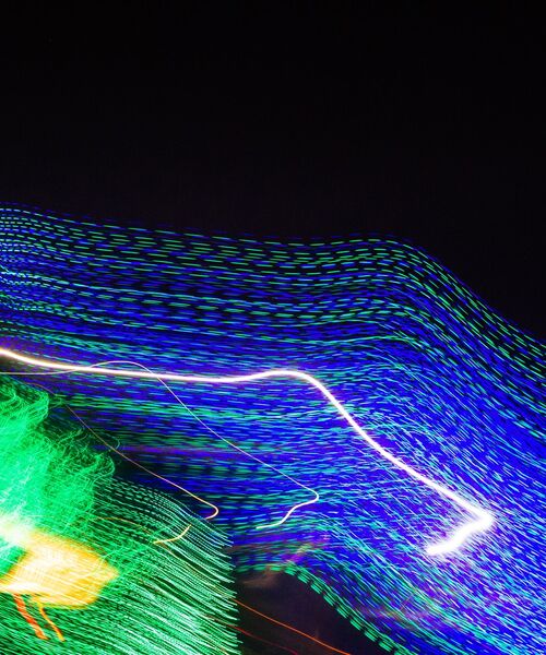 Abstrakte Lichtspuren in Blau, Grün und Weiß vor schwarzem Hintergrund.