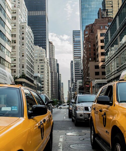 Straßenszene in einer Großstadt mit gelben Taxis und Hochhäusern.