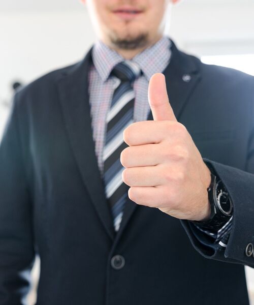 Geschäftsmann im Anzug zeigt Daumen nach oben.