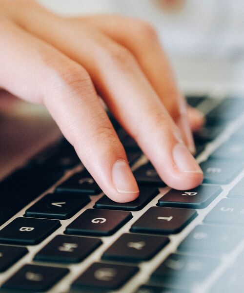 Hand tippt auf einer Laptop-Tastatur.