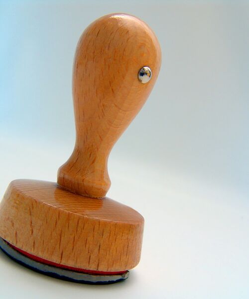 Holzstempel mit rundem Griff auf hellem Hintergrund.