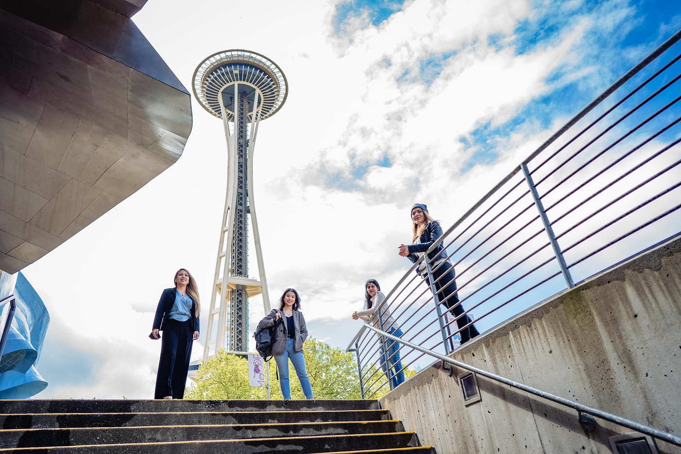 Vier junge Menschen stehen lachend vor der Space Needle in Seattle.